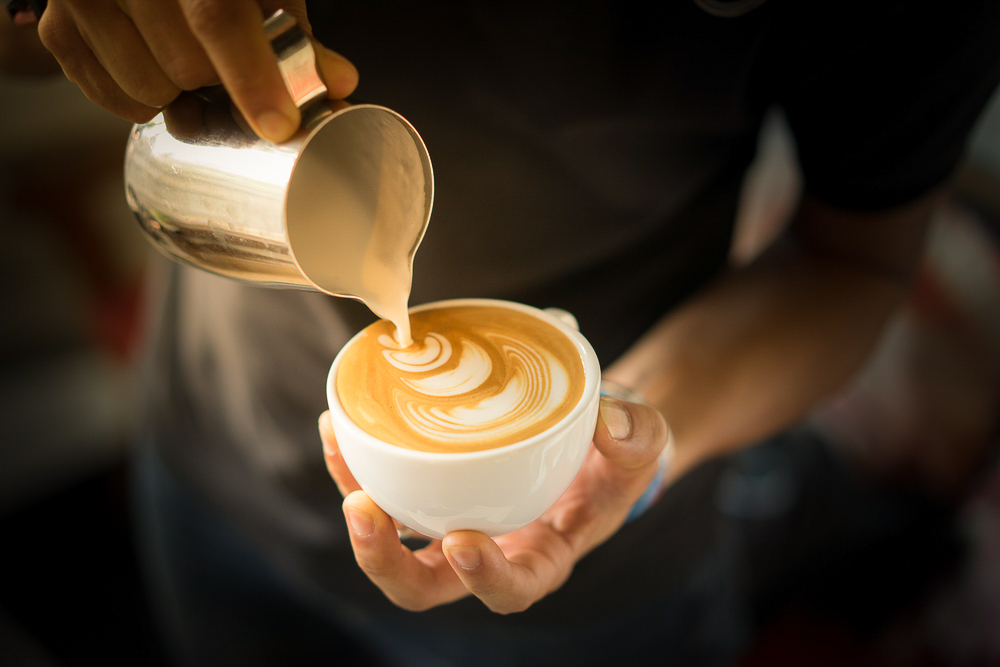 hand on barista making latte cafe, cup of coffee with beautiful Latte art on white cup